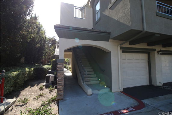 Front view of a multi-story building with garage and stairway entrance.