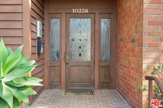 Front entrance of a house with wooden door and decorative glass panels.