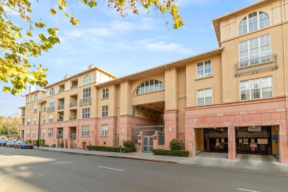 Front view of a multi-story residential building with arched windows and gated entrance.