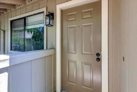 Front view of a house entrance with a tan door and a lantern-style light.