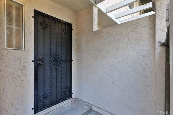Exterior view of a building entrance with a decorative metal door and textured walls.
