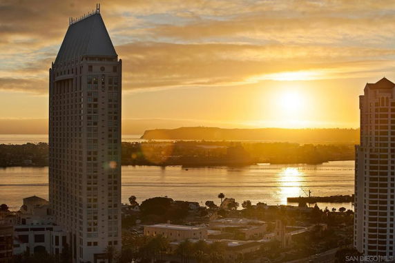 Panoramic view from a high-rise building overlooking water and cityscape at sunset.