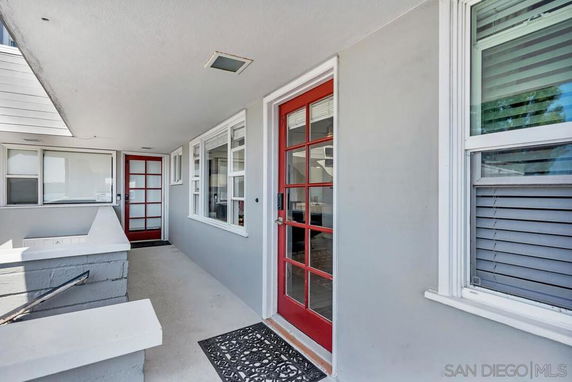 Front view of a house with red framed glass doors and white walls.