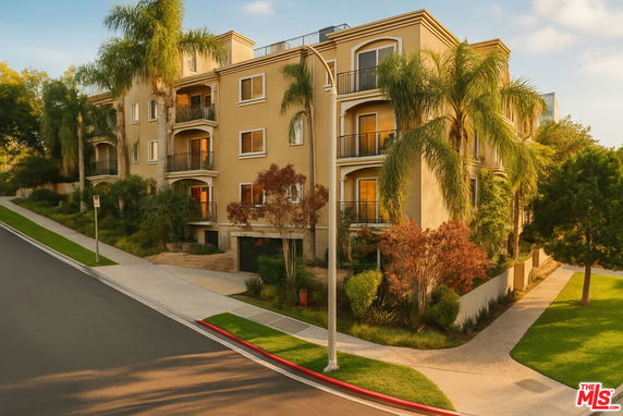Front view of a multi-story building with balconies and surrounding greenery.