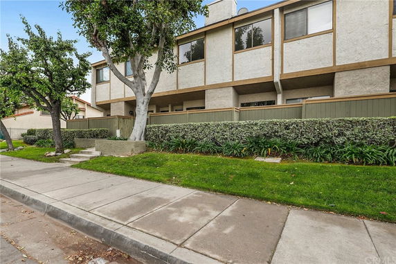 Front view of a multi-story residential building with fenced patio areas.