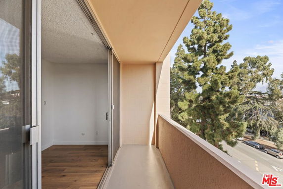 Balcony view with trees and a glimpse of the street below.