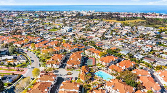 Aerial panoramic view of a residential area with red-roofed houses near the coast.