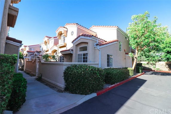 Front view of a multi-story house with a stucco exterior and tile roof.