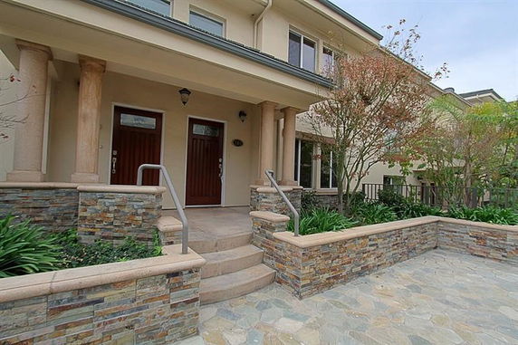 Front view of a two-story house with stone accent and pillars.