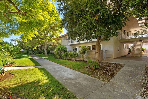 Front view of a two-story apartment building with a walkway and trees.