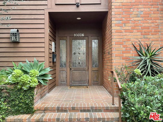 Front view of a house entrance with wooden and brick siding.