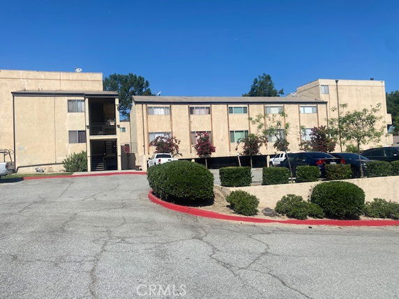 Front view of a multi-story apartment building with parking area.
