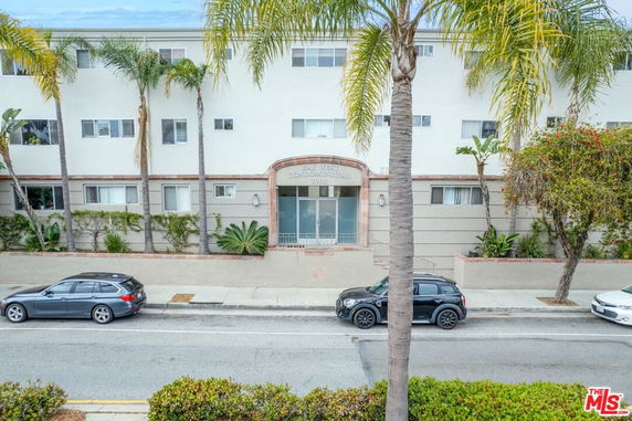 Front view of a multi-story condominium building with palm trees.