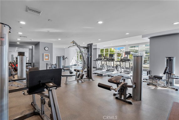 Interior view of a gym with various exercise equipment and large windows.