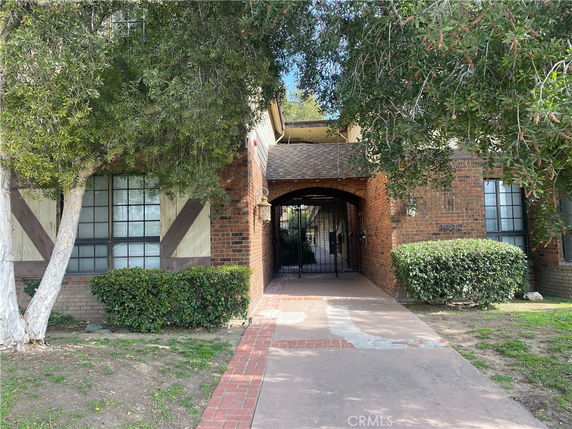 Front view of a brick building entrance with a gated archway.