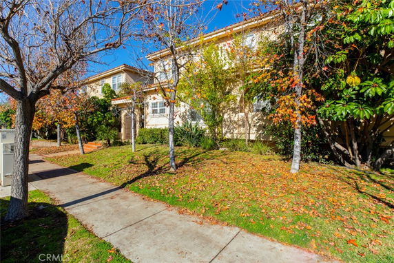 Front view of a multi-story house with a landscaped yard and trees.