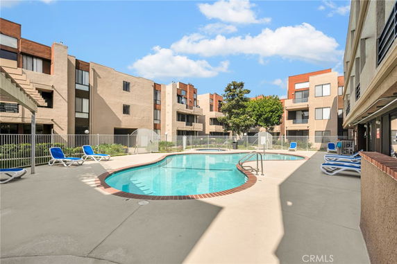 Outdoor swimming pool area surrounded by multi-story residential buildings.