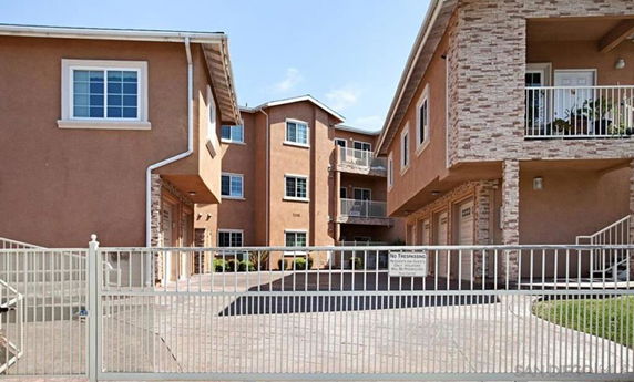 Front view of a multi-story apartment building with a gated entrance.