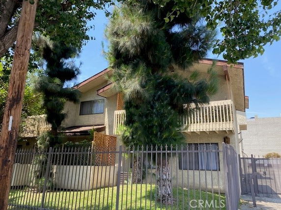 Front view of a multi-story house with trees and a fence.