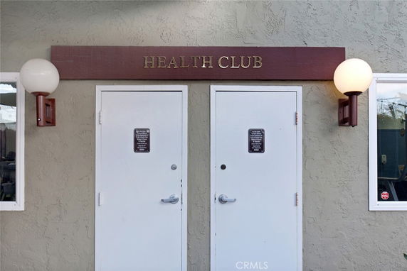 Entrance to a health club with two white doors and exterior lighting.