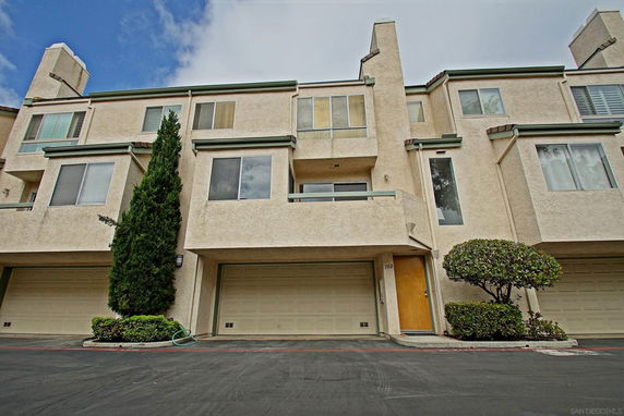 Front view of a multi-story townhouse with garages on the ground level.