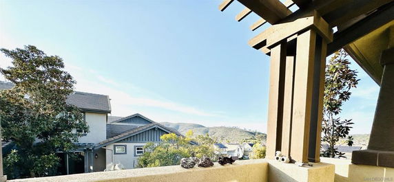 Panoramic view from a balcony overlooking houses and distant hills.
