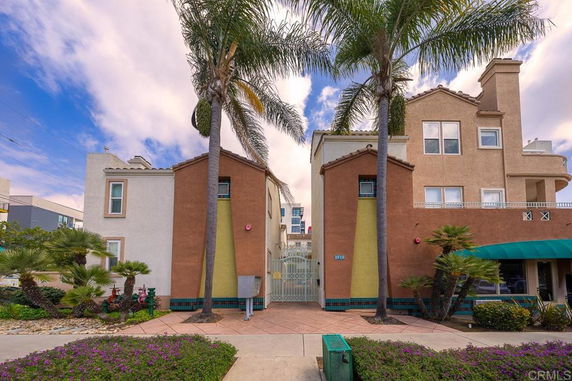 Front view of a multi-story building with a gated entrance and palm trees.