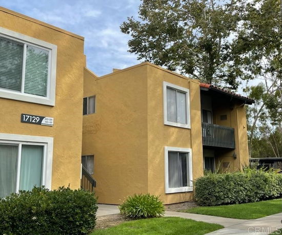 Front view of a two-story building with yellow stucco walls and a balcony.