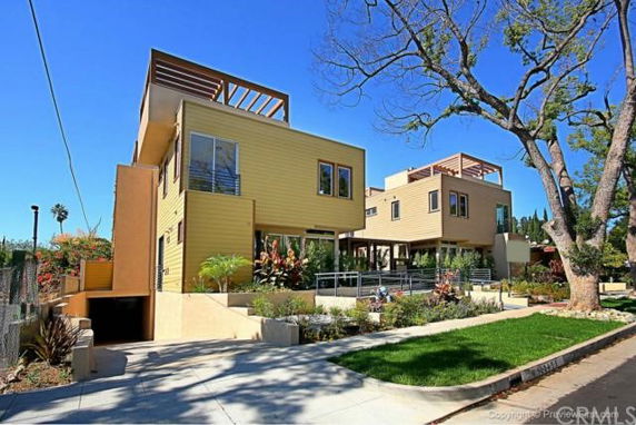 Front view of a modern multi-story house with a flat roof and wooden exterior.