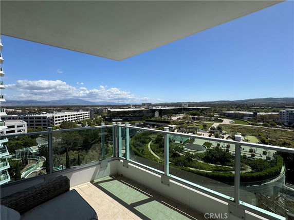 Panoramic view from a building balcony overlooking surrounding area with distant mountains and nearby buildings.
