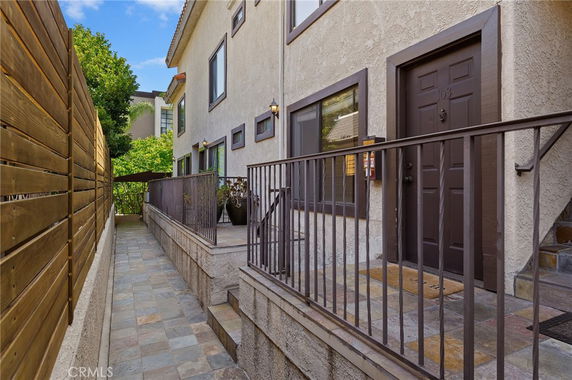 Side view of a multi-story house with a pathway and railing.