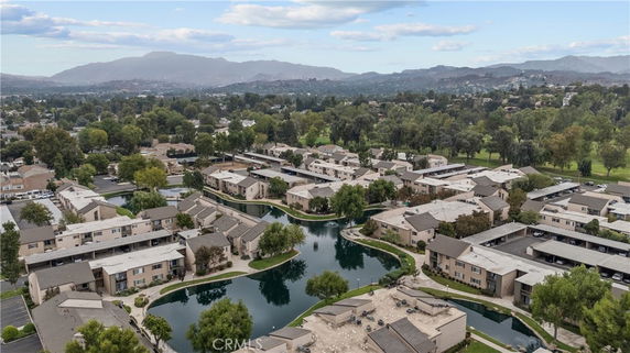 Aerial view of residential buildings surrounded by landscaped areas and a small body of water.