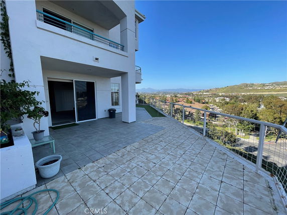Panoramic view from a building balcony overlooking a suburban area with hills in the background.