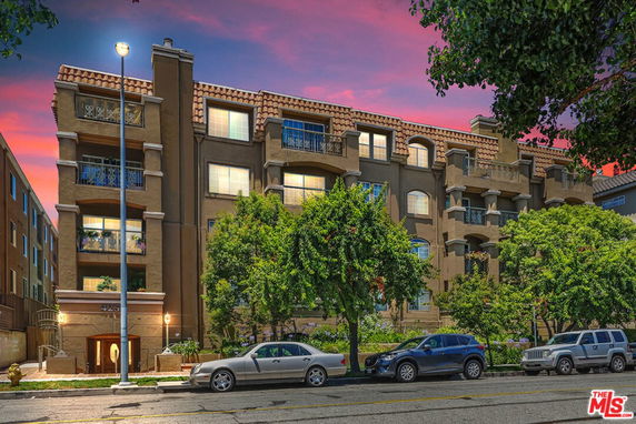 Front view of a multi-story building with balconies and a tiled roof.