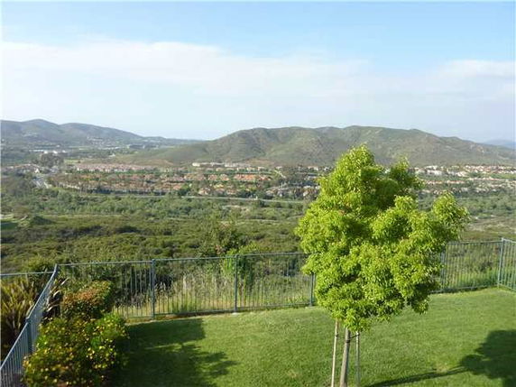 Panoramic view of rolling hills and residential area seen from a green lawn.