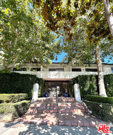 Front view of a two-story building with trees and brick steps leading to the entrance.