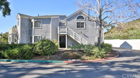 Front view of a two-story residential building with exterior stairs and gray siding.