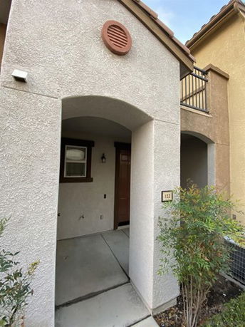 Front view of a house with an arched entryway and a second-story balcony.