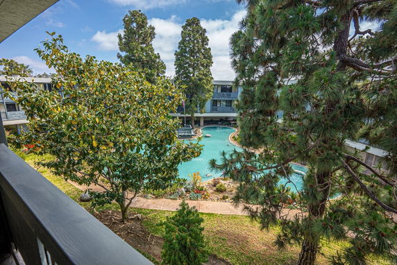 View of a swimming pool surrounded by trees in a residential complex.
