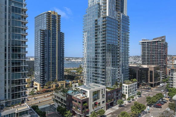 Aerial view of a cityscape with high-rise buildings and a body of water in the background.