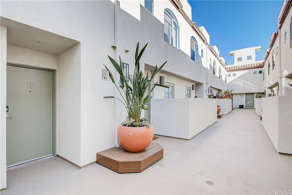 Exterior view of a multi-story building with white walls and potted plants.