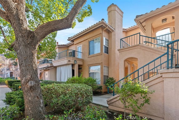 Front view of a two-story house with balconies and a sloped walkway.