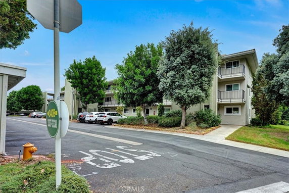 Front view of a multi-story residential building with balconies and nearby parking.