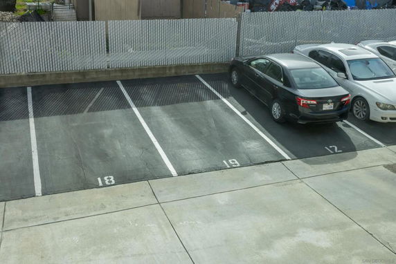 Outdoor parking lot with numbered parking spaces and parked cars.