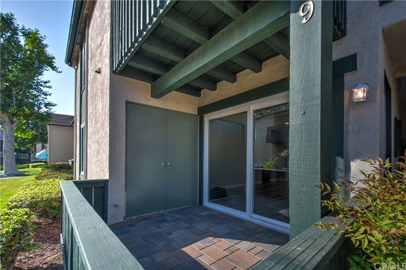 Front view of a building entrance with sliding glass doors and a small patio area.