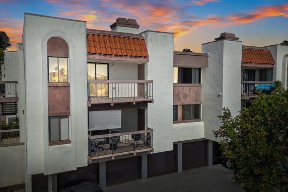 Front view of a multi-story building with balconies and a terracotta tiled roof.