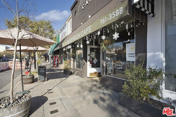 Street view of a cafe with a sign reading 'Caoti Pizza Cafe' and outdoor seating.