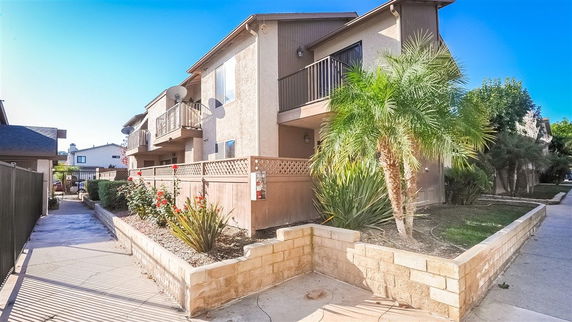 Front view of a two-story residential building with balconies and a small garden.
