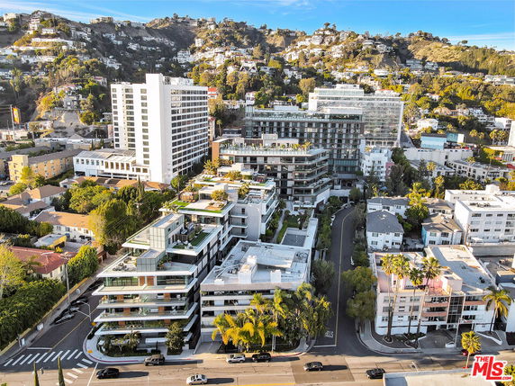 View of multiple buildings in an urban setting with hills in the background.