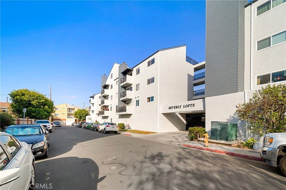 Front view of a multi-story building with balconies and a driveway entrance labeled 'Beverly Lofts'.